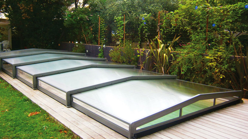 Abri de piscine bas en verre sur piscine en bois Odyssea Alladin Concept